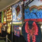 red, blue, brown and green quilted items hangin in the hallway