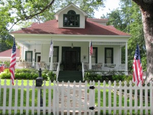 a house with a white picket fence and 4 american flags in the yard