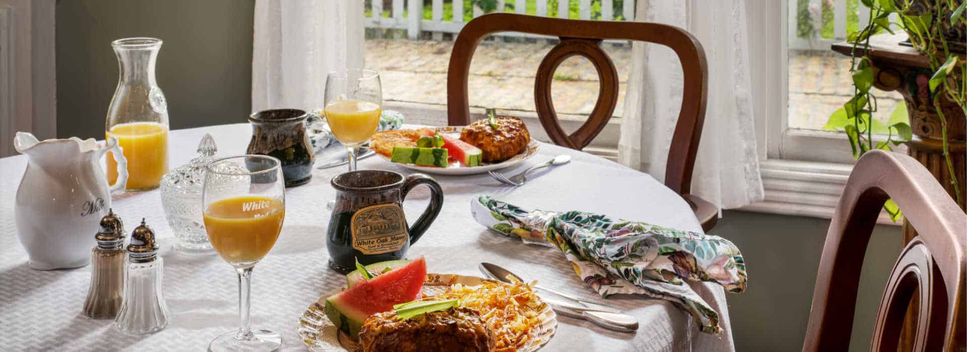 table with breakfast plates filled with foo, coffee cup and orange juice glasses