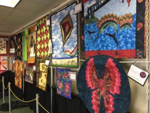 red, blue, brown and green quilted items hangin in the hallway