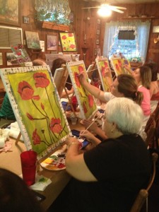 A group of women painting at the tables set up down the center of the restaurant.