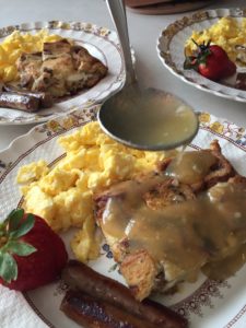 cinnamon bread breakfast bake with scramble eggs and a strawberry on an antique plate with yellow flowers.