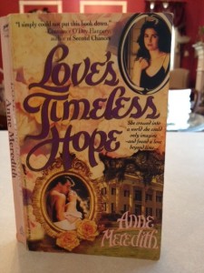 The cover of a romance novel by Anne Meredith. It has a picture of a large Greek revival home on it  and two oval pictures. One picture is of the novelist and the other is a man and woman in a loving embrace.