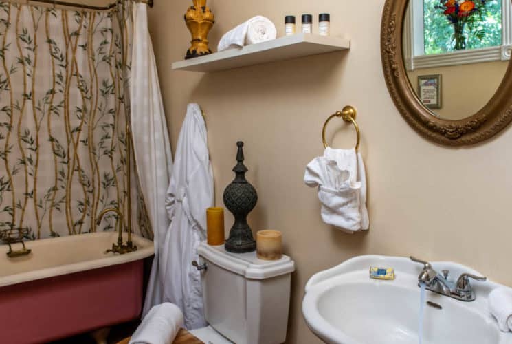 bathroom with a white sink and toilet and a pink old fasioned bathtub and shower