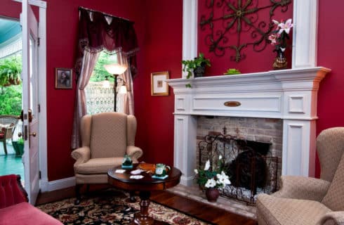 red room with a white fireplace and chairs