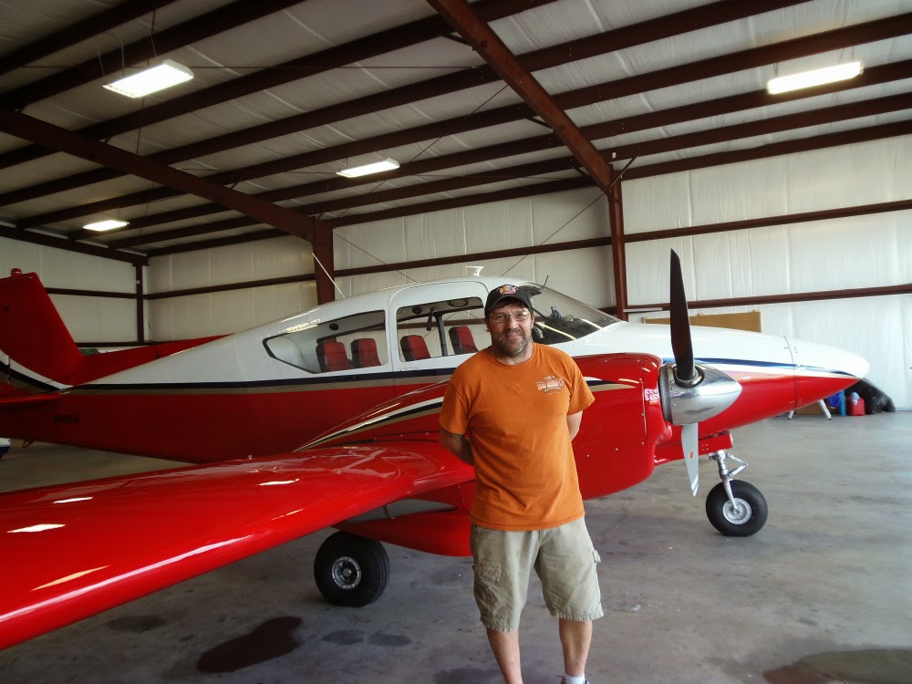 Red plane in the hanger with David standing in front of it.