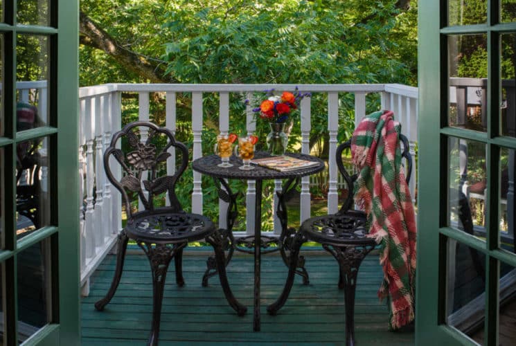 table with flowers and chairs on a green and white balcony