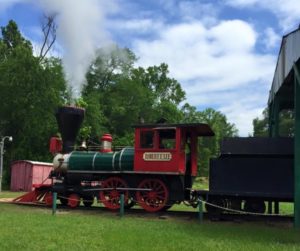 red steam train with a green boiler on a bright blue day