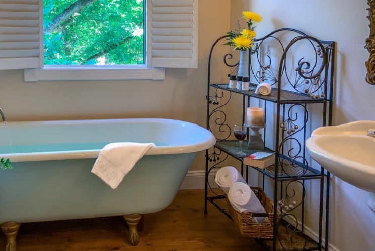 claw foot tub with a white towel below a window