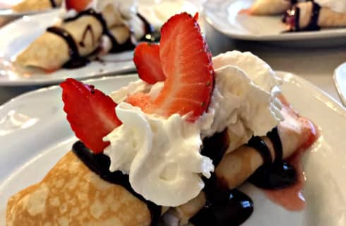 crepes with whip cream, chocolate sauce and strawberries