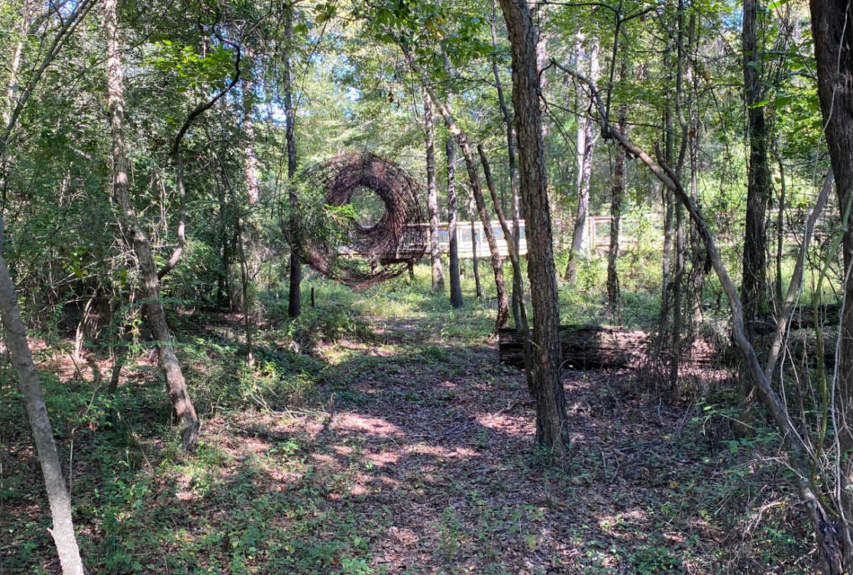 wire art hanging in the green trees