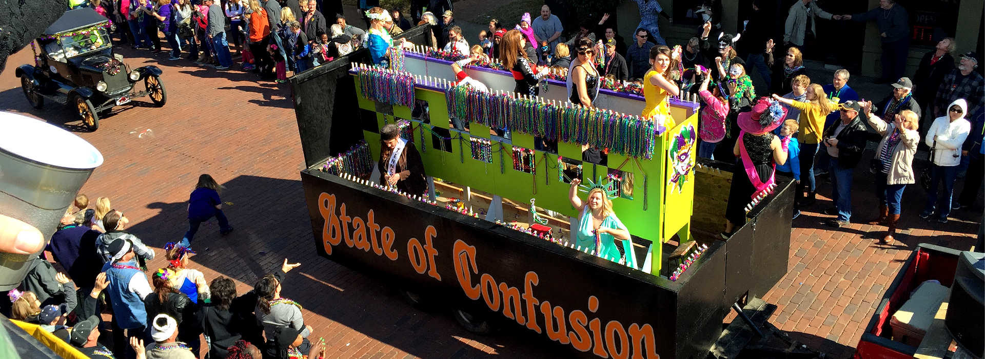 float with black, yellow and purple tower with ladies throwing mardi gras bead into the crowd
